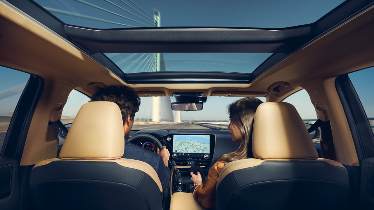 A man and woman driving a Lexus across a bridge
